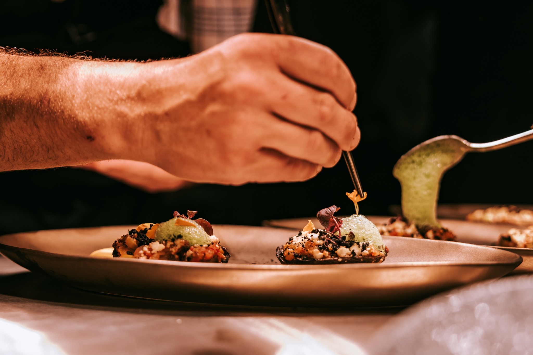 Een chef werkt verfijnde gerechten zorgvuldig af met een pincet