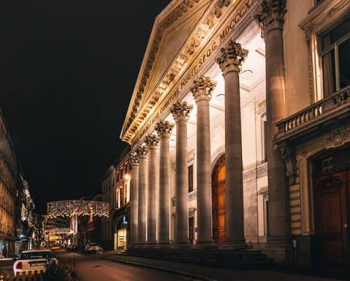 De verlichte zuilengevel van Aula UGent bij avond