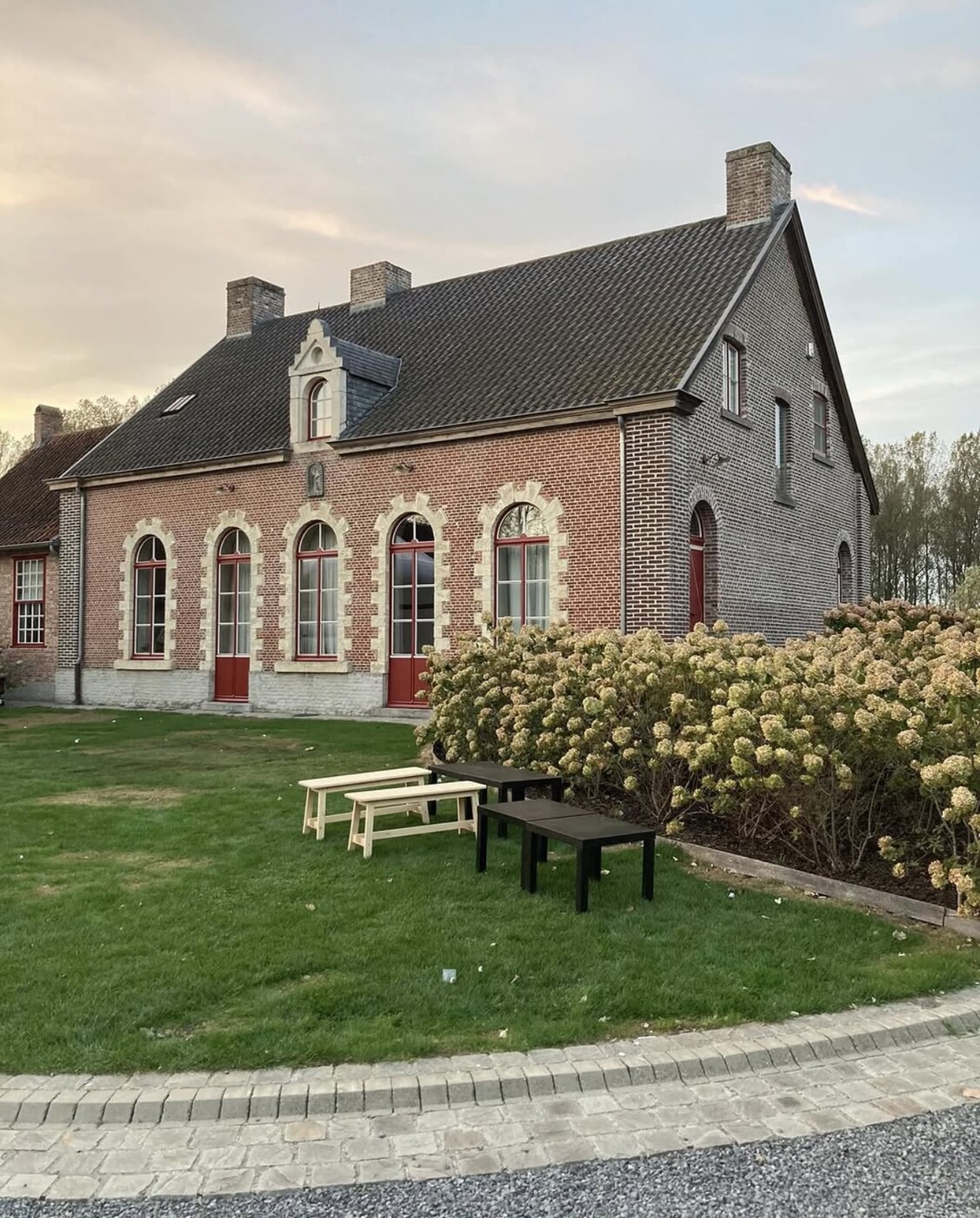 Buitenaanzicht van Schuur Dierickx met de tuin in warm avondlicht